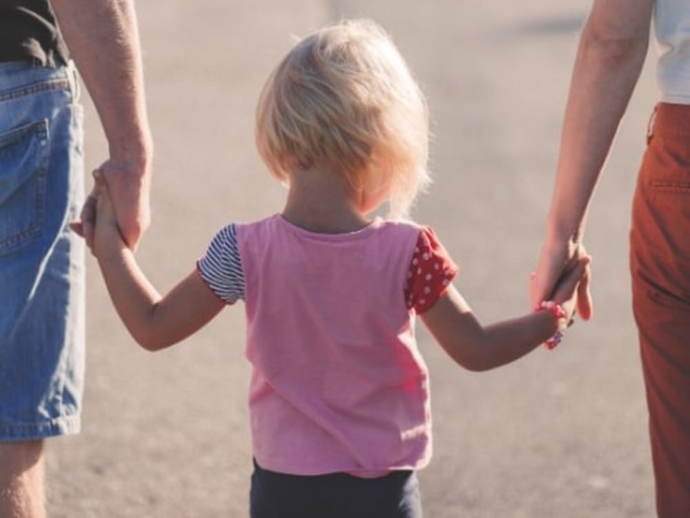 Child holding hands with two adults